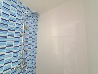 Modern bathroom with blue striped wall tiles and glass shower