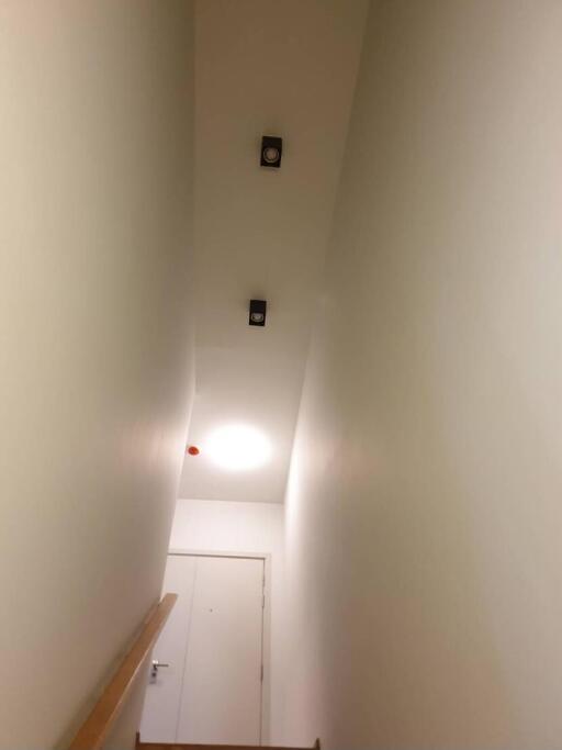 Narrow corridor with white walls, ceiling lamp, and closed door