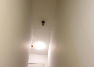 Narrow corridor with white walls, ceiling lamp, and closed door