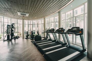 Modern gym with treadmills and exercise equipment in a well-lit space with large windows