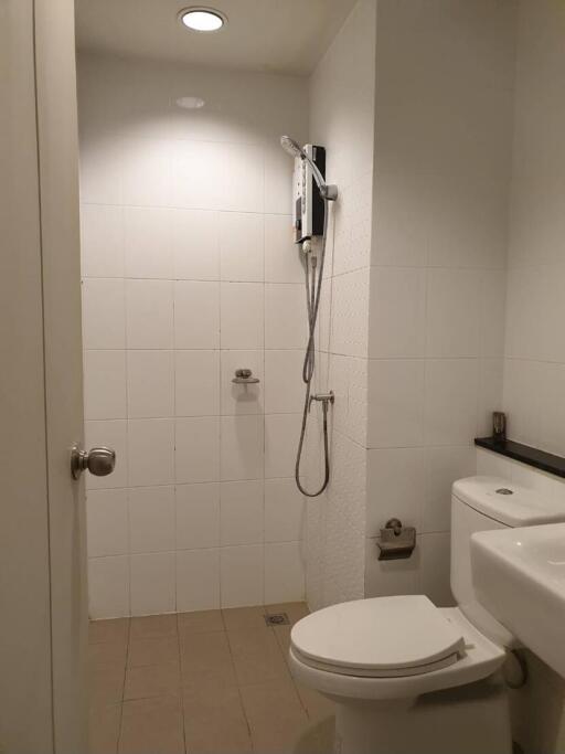Compact bathroom with white tiles featuring shower, toilet, and sink