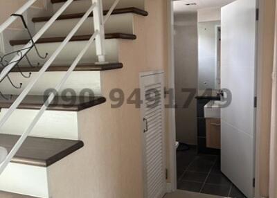 Modern staircase with wooden steps in a well-lit hallway leading to rooms