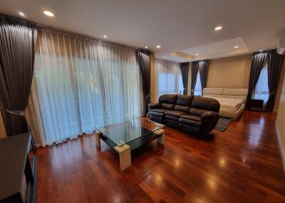 Spacious living room with hardwood floors, large windows, and modern furniture