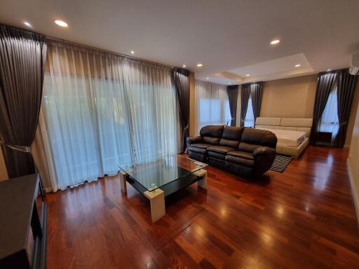 Spacious living room with hardwood floors, large windows, and modern furniture