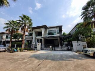 Spacious two-story house with a large driveway and tropical palm trees