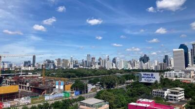 Expansive cityscape view from a high vantage point, showcasing urban development and skyline under a clear blue sky