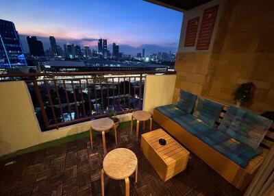 Cozy balcony with city skyline view at dusk featuring seating arrangement