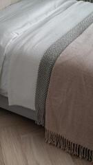 Cozy bedroom detail with elegant bedding and textured throw