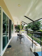 Spacious balcony with outdoor seating and a view of the surrounding greenery