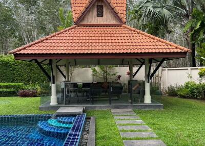 Covered patio area by the poolside with tropical landscaping