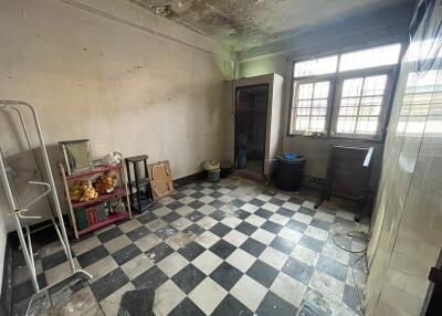 Spacious room in need of renovation with checkered flooring, windows, and assorted items