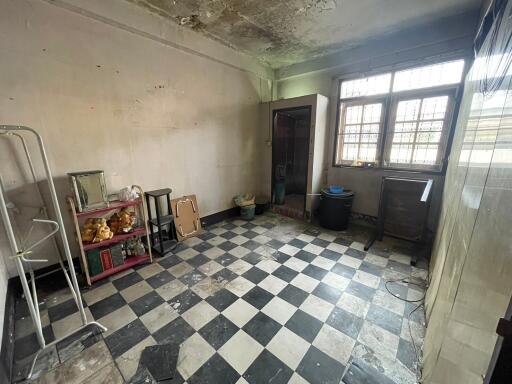 Spacious room in need of renovation with checkered flooring, windows, and assorted items