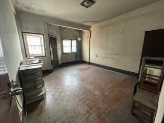 Spacious unfurnished room with parquet flooring, multiple windows, and in need of renovation