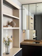 Modern hallway interior with decorative shelf, vase with flowers, and mirrored wardrobe