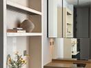 Modern hallway interior with decorative shelf, vase with flowers, and mirrored wardrobe