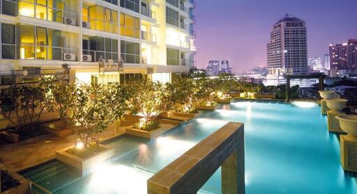 Luxurious building exterior with illuminated swimming pool at twilight