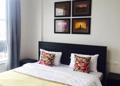 Modern bedroom with a neatly made bed, decorative pillows, and framed artwork on the wall