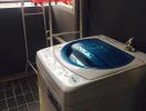 Compact laundry room with a top-loading washing machine and clothes drying rack