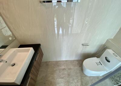 Contemporary bathroom with glossy tiled walls, modern fixtures, and natural light