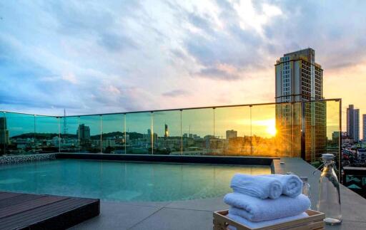 Rooftop swimming pool with city skyline at sunset