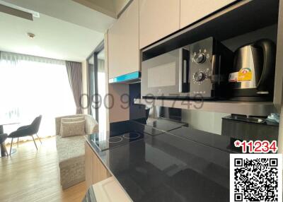 Modern kitchen with black countertops and built-in appliances, leading to an open living area