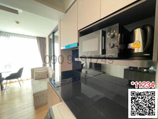 Modern kitchen with black countertops and built-in appliances, leading to an open living area