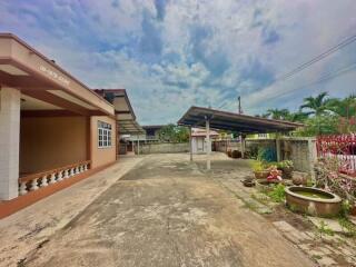 Spacious outdoor area with a carport and driveway in front of a residential building