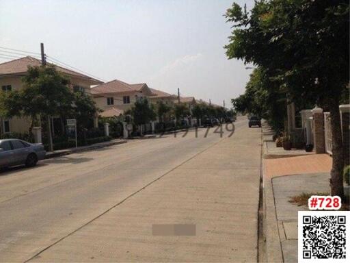 Paved street in a residential neighborhood with houses and parked cars