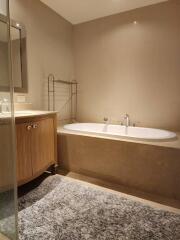 Elegant bathroom with a large bathtub, towel warmer, and wooden vanity cabinet