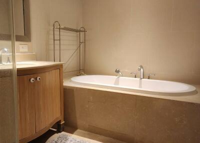 Elegant bathroom with a large bathtub, towel warmer, and wooden vanity cabinet