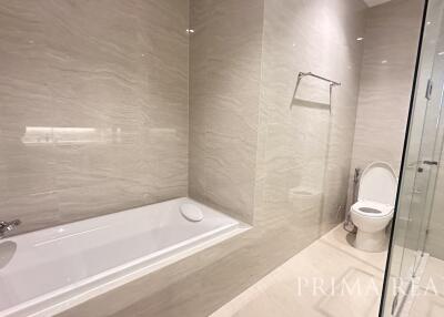 Modern bathroom with elegant finishes, featuring a bathtub, glass shower stall, and toilet