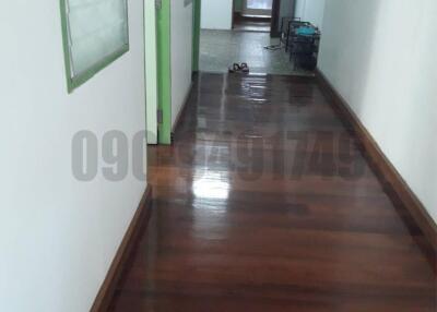 Wooden floored hallway leading to rooms with green doors