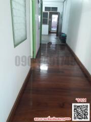 Wooden floored hallway leading to rooms with green doors