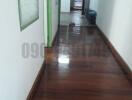 Wooden floored hallway leading to rooms with green doors