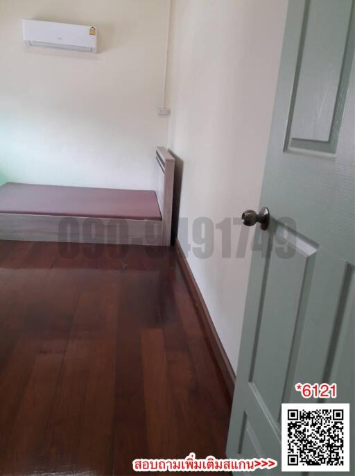 Simple bedroom interior with wooden flooring and white walls