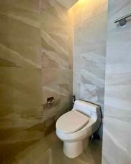 Modern bathroom with beige tiles and wall-mounted toilet