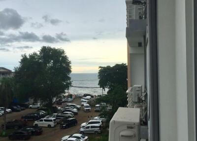 View from balcony featuring sea view, parking area, and neighboring building