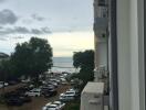 View from balcony featuring sea view, parking area, and neighboring building