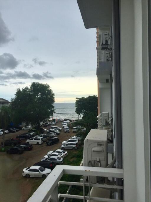 View from balcony featuring sea view, parking area, and neighboring building