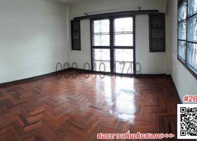 Spacious and bright empty room with polished wooden flooring and large windows