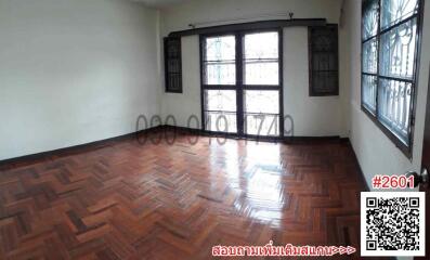 Spacious and bright empty room with polished wooden flooring and large windows