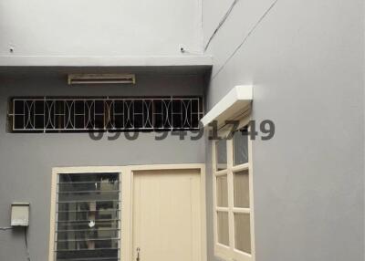 Beige door on a modern building exterior with windows and narrow walkway