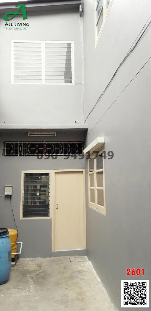 Beige door on a modern building exterior with windows and narrow walkway