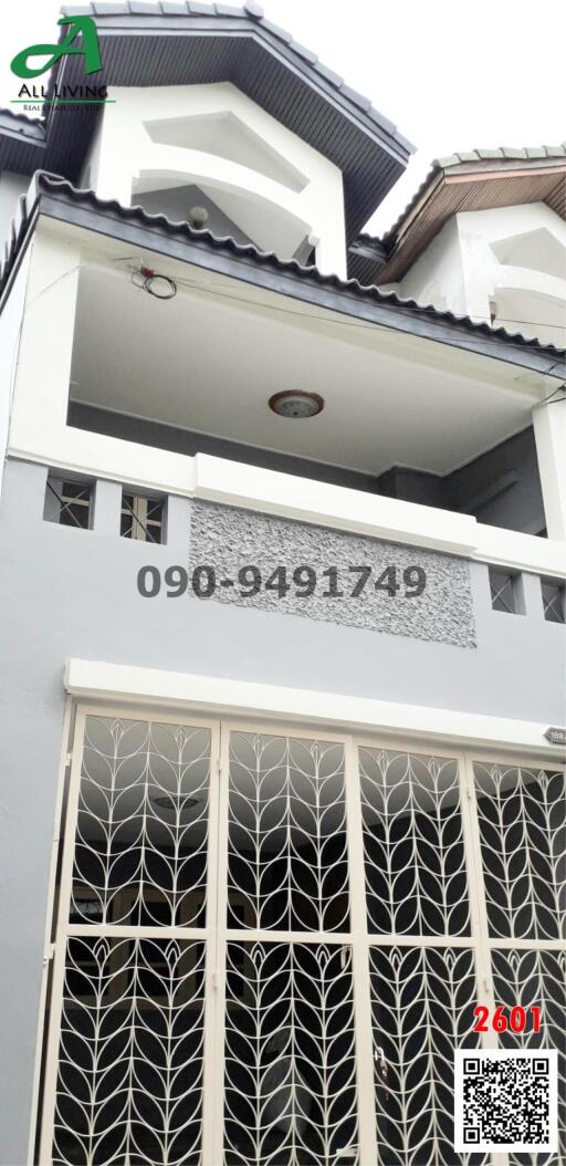 Exterior view of a modern multi-story residential building with decorative security grille and balcony