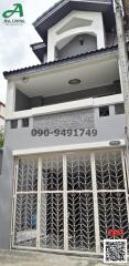 Three-story residential building exterior with white walls and decorative security grilles