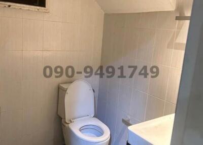 Compact white tiled bathroom with toilet and sink