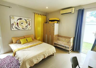 Bright bedroom with a large bed and a baby crib