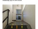 Office hallway with directional arrows on the floor leading to a glass door