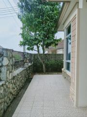 Spacious tiled patio with a green tree and stone wall