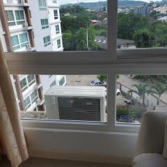 A room with a large window showing an air conditioning unit and a view of nearby buildings and greenery